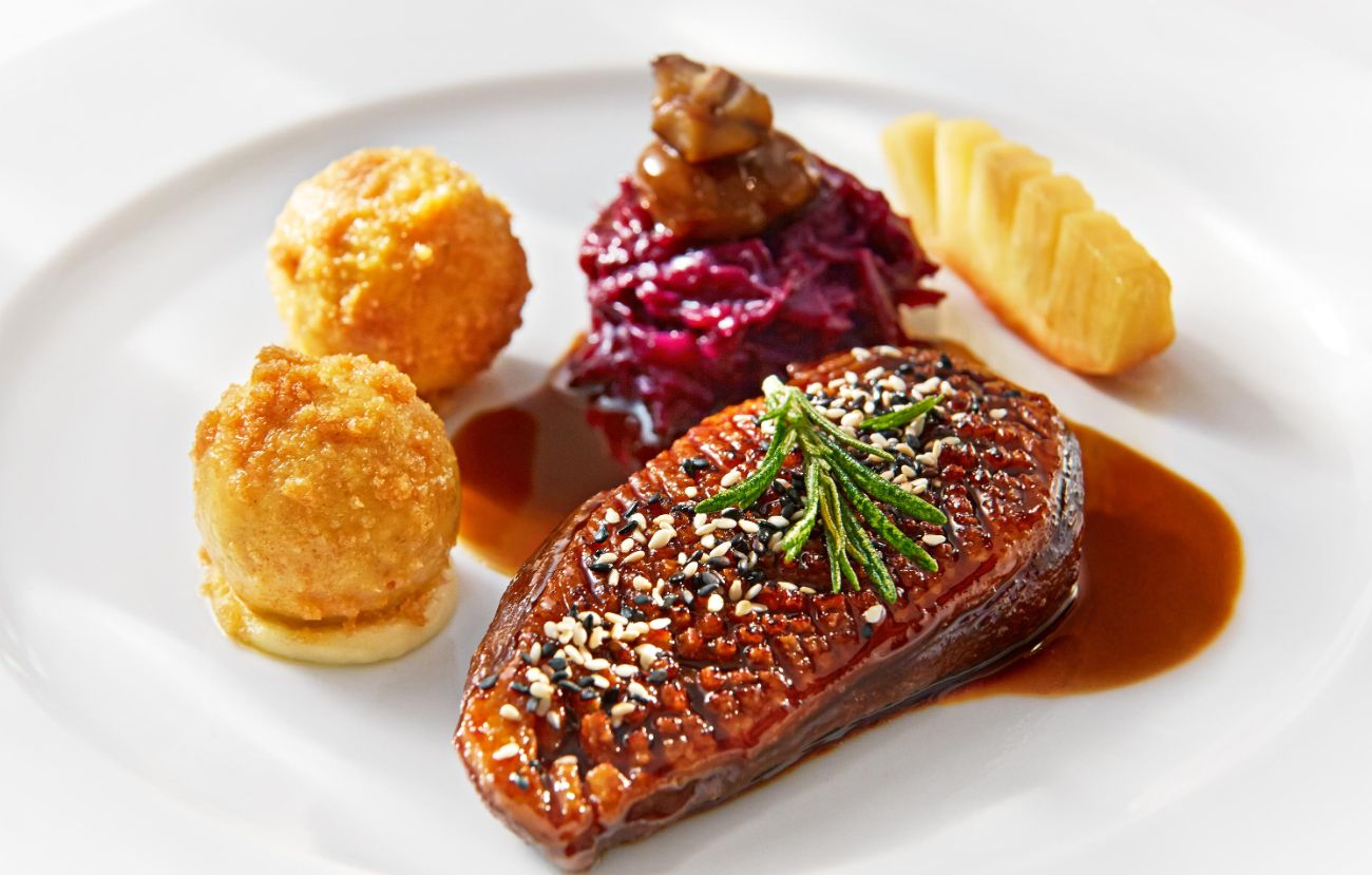 Der Hauptgang im PALAZZO Berlin: Lackierte Entenbrust mit Tannenhonig und schwarzem Pfeffer auf karamellisiertem Rotkohl, dazu kleine Kartoffelknödel und Kardamom-Sauce