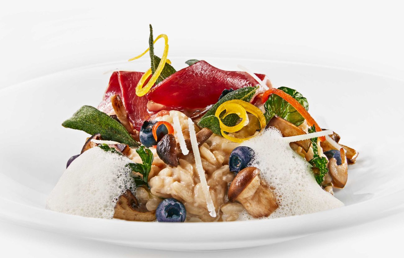 Der Zwischengang im PALAZZO Hamburg: Risotto mit Waldpilzen, Heidelbeeren, gebackenen Kräutern und geräucherter Gänsebrust