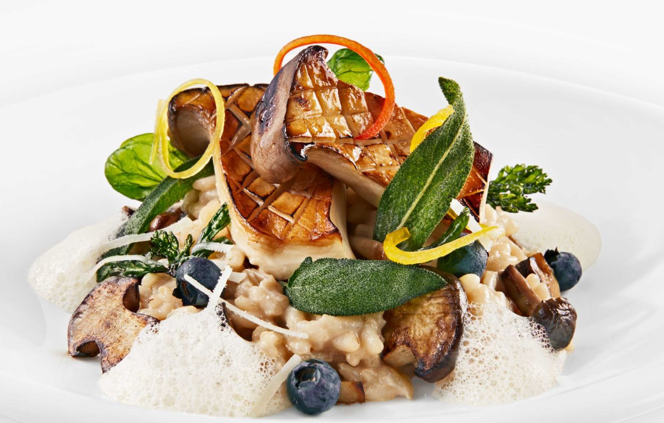 Der vegetarische Zwischengang im PALAZZO Hamburg: Risotto mit Waldpilzen, gebratenem Kräuterseitling, Heidelbeeren und gebackenen Kräutern