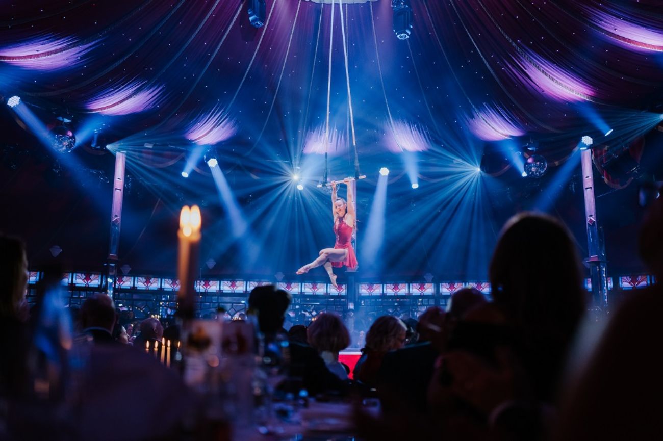 Die Künstlerin Judit Horvath hängt mit ihren Armen am Trapez im PALAZZO Spiegelpalast.