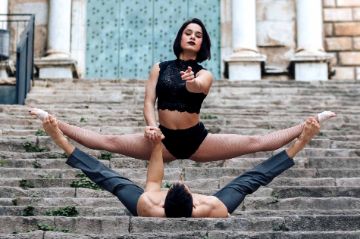 Das Duo Loyalty performt einen Fußstand im Spagat auf einer Treppe.