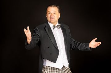 Moderator und Zuaberer Steve Eleky posiert lächelnd auf der Bühne.
