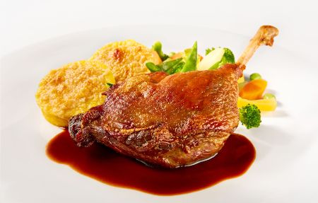 Der Hauptgang Confierte Entenkeule an Balsamico-Jus mit überbackenen Polentatalern und Wurzelgemüse im PALAZZO Berlin.