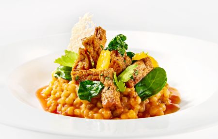 Vegetarischer Zwischengang „Risotto“ von Fregola sarda mit Spinat, gebackenem Tofu, grünen Oliven und Tomatenfond im PALAZZO Berlin.