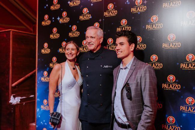 Starkoch Alexander Herrmann posiert mit Gästen vor der Fotowand zur Premierenfeier des PALAZZO Nürnberg.