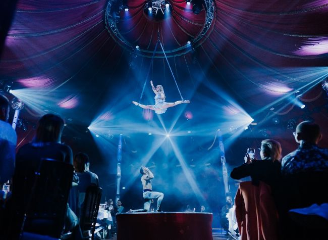 Eine Künstlerin hängt im Spagat in den Strapaten im Spiegelpalast. 