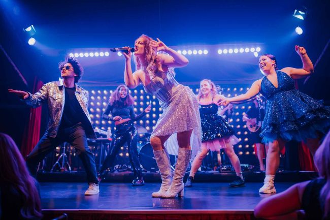 Sängering Niamh Shoyinka und weitere Artisten tanzen auf der Bühne im PALAZZO Spiegelpalast.