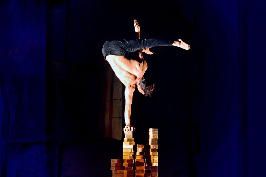 Der Handstand-Artist Mukhamadi macht einen einarmigen Handstand.